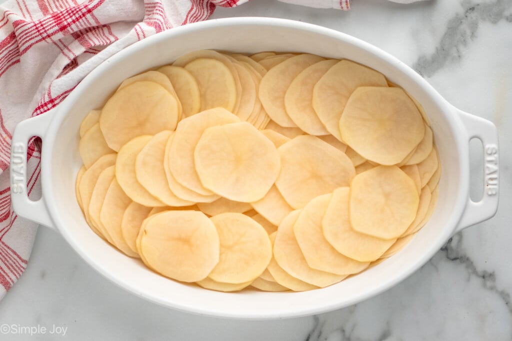 Overhead view of a baking dish of Potatoes Au Gratin recipe with sliced potatoes - 8