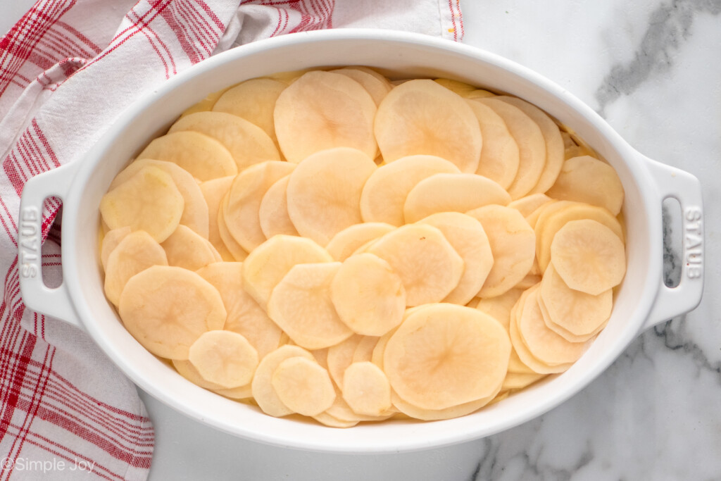 Overhead view of a baking dish of Potatoes Au Gratin recipe with sliced potato layer