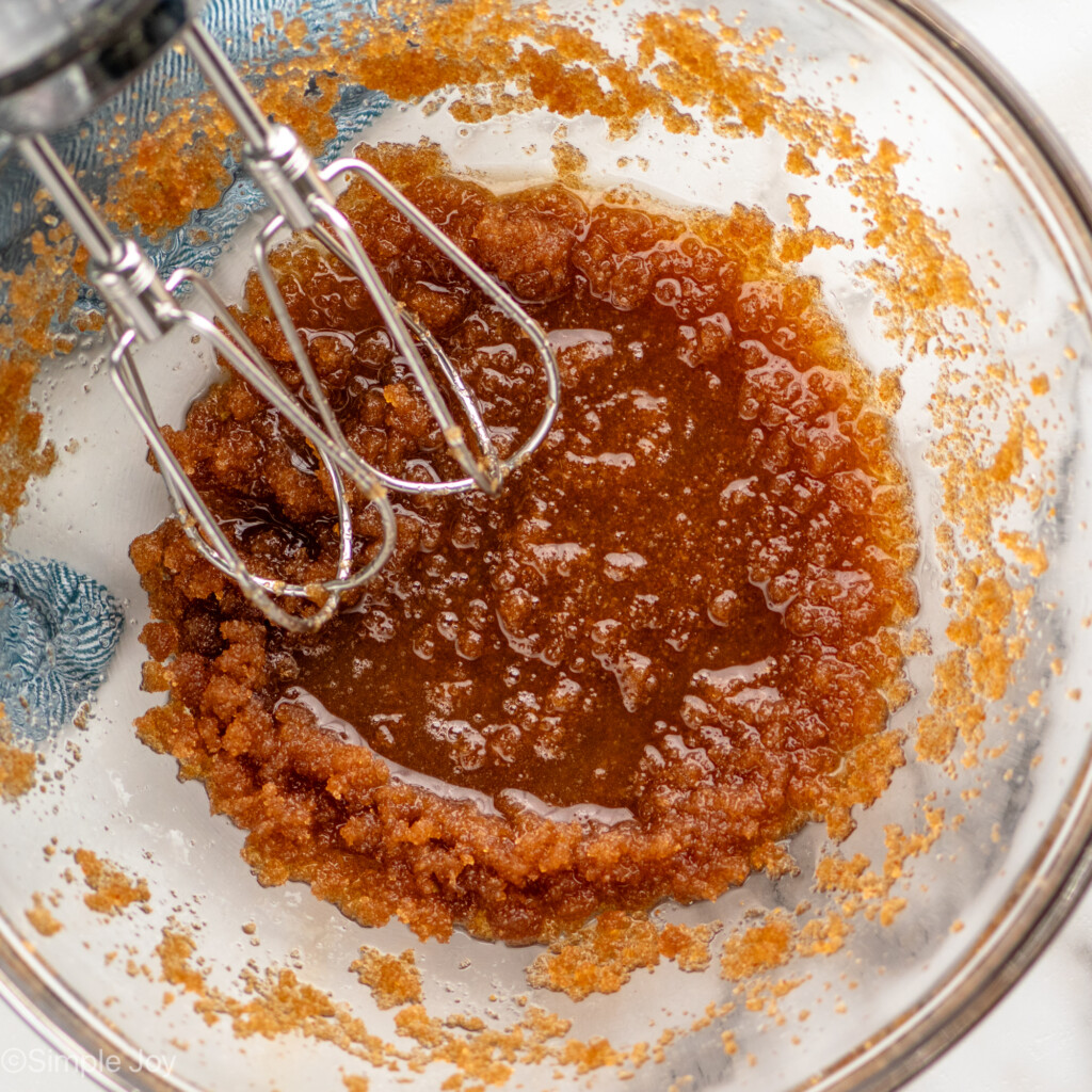Overhead view of mixing bowl with wet ingredients and hand mixer for Brown Butter Chocolate Chip Cookies recipe