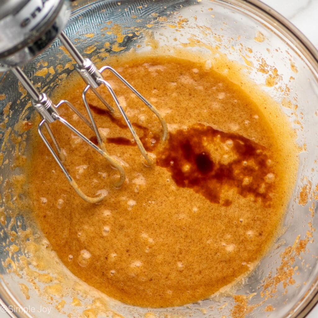 Overhead view of a mixing bowl of wet ingredients and hand mixer for Brown Butter Chocolate Chip Cookies recipe
