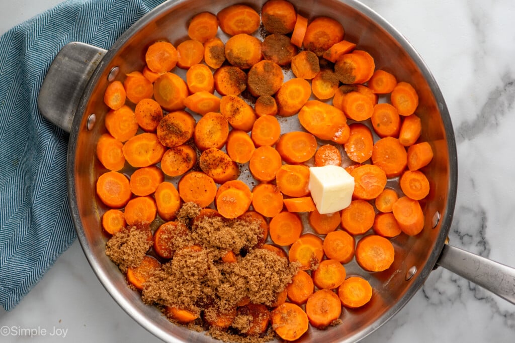 Overhead view of a skillet with chopped carrots, butter, and seasonings for candied carrots recipe. - 8