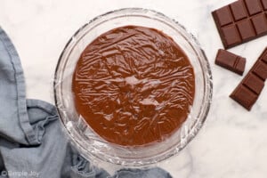 plastic wrap pressed to the top of a bowl of chocolate pudding