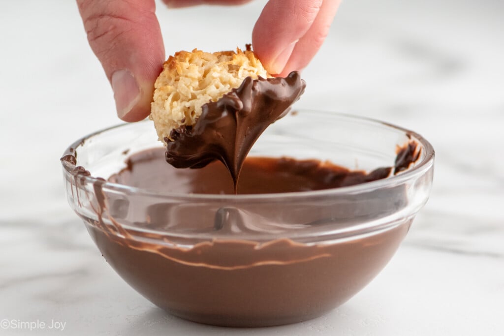 Side view of person's hand dipping Coconut Macaroons into bowl of melted chocolate - 8