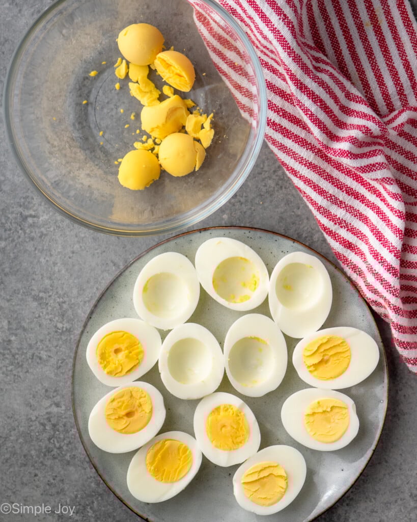 Overhead view of hard boiled eggs peeled and cut in half with some of the yolks removed for Deviled Eggs recipe