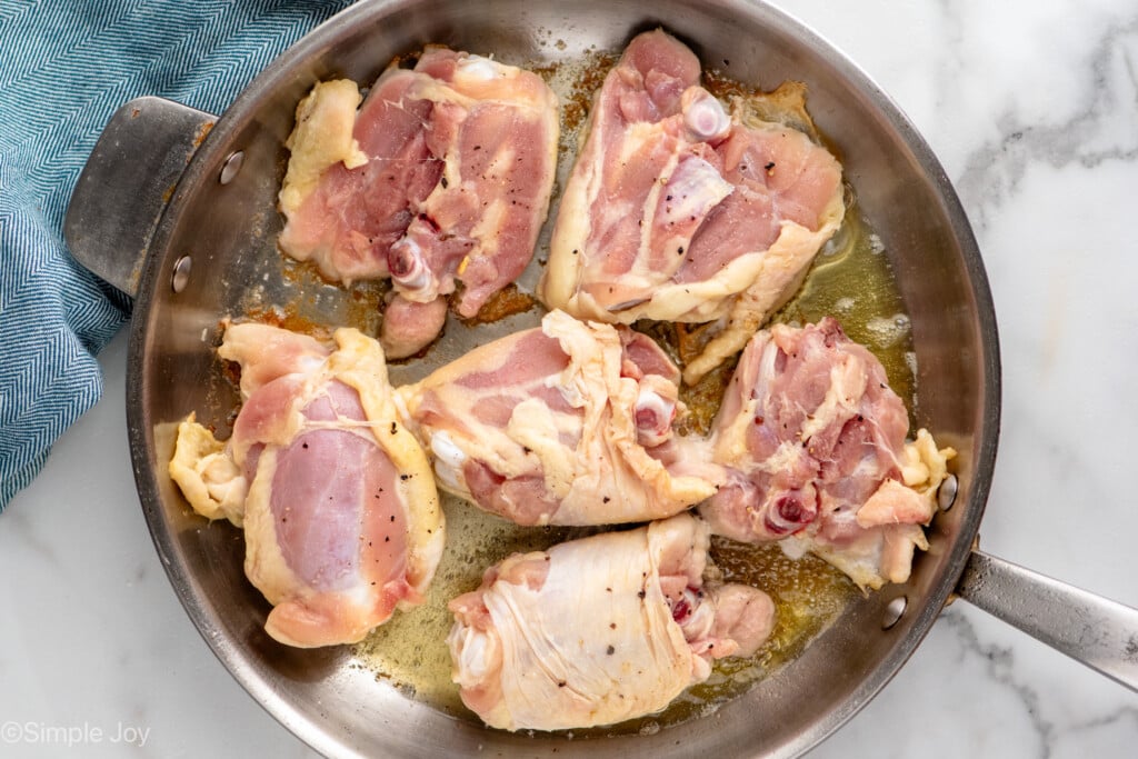 Overhead view of a skillet of raw chicken thighs for Honey Garlic Chicken Thighs recipe