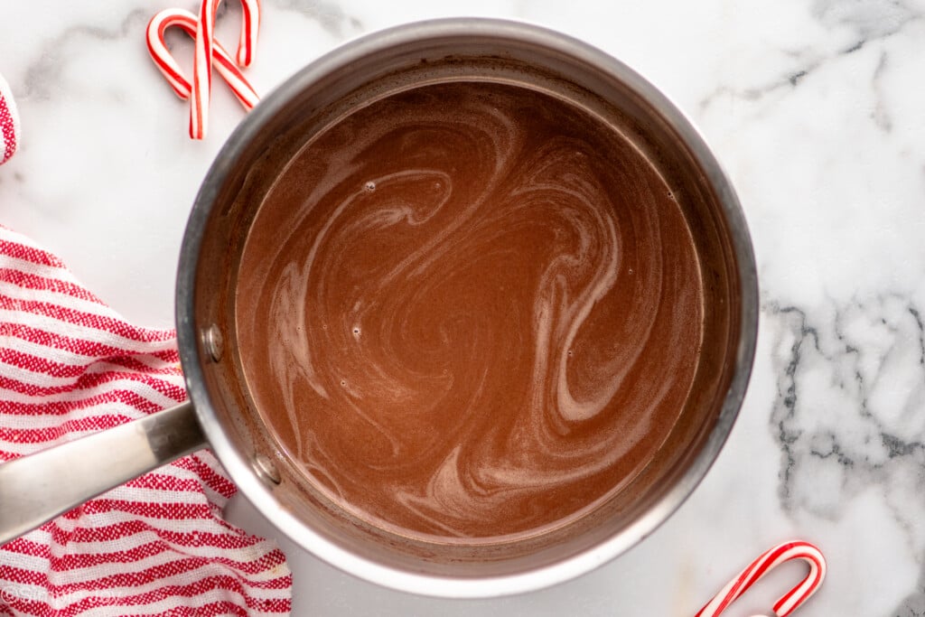 Overhead view of a saucepan of Peppermint Hot Chocolate recipe with candy canes beside - 5