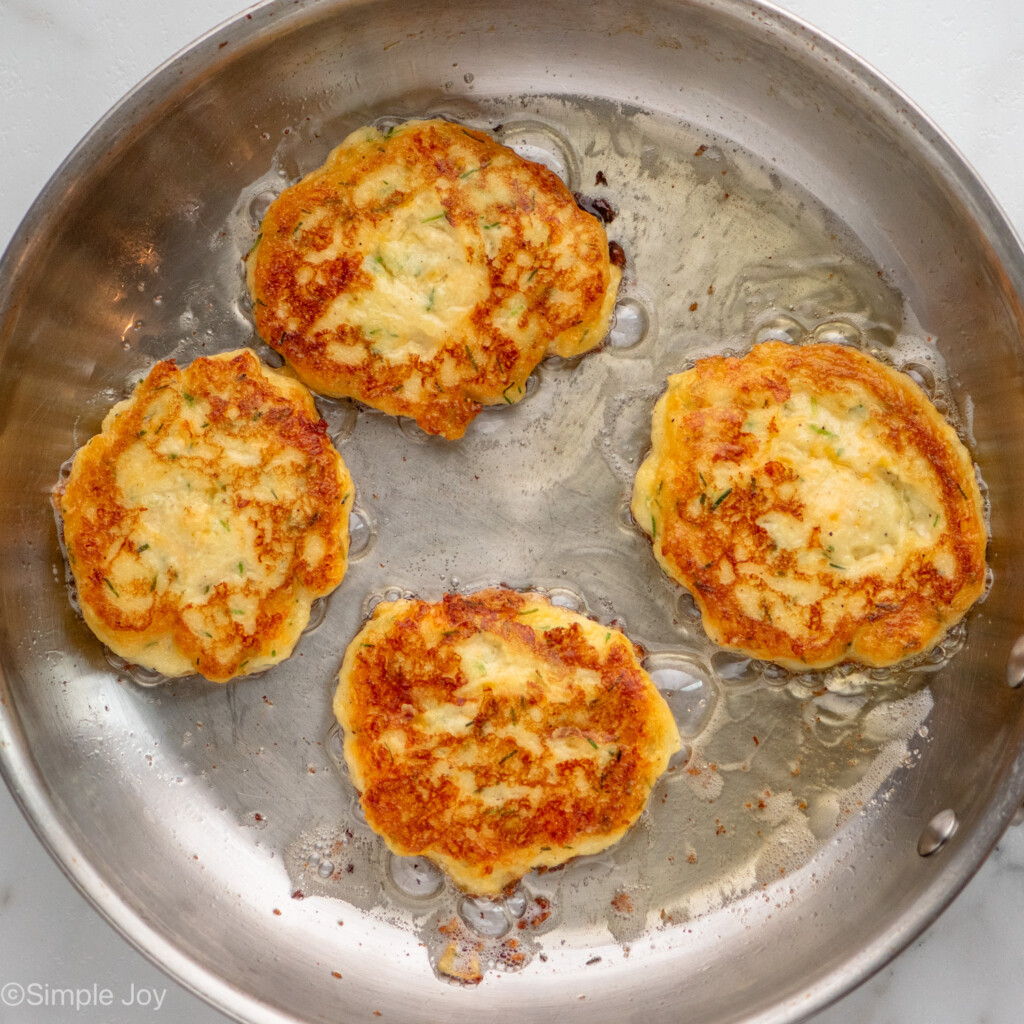 Overhead view of a skillet with Mashed Potato Pancakes frying in it.