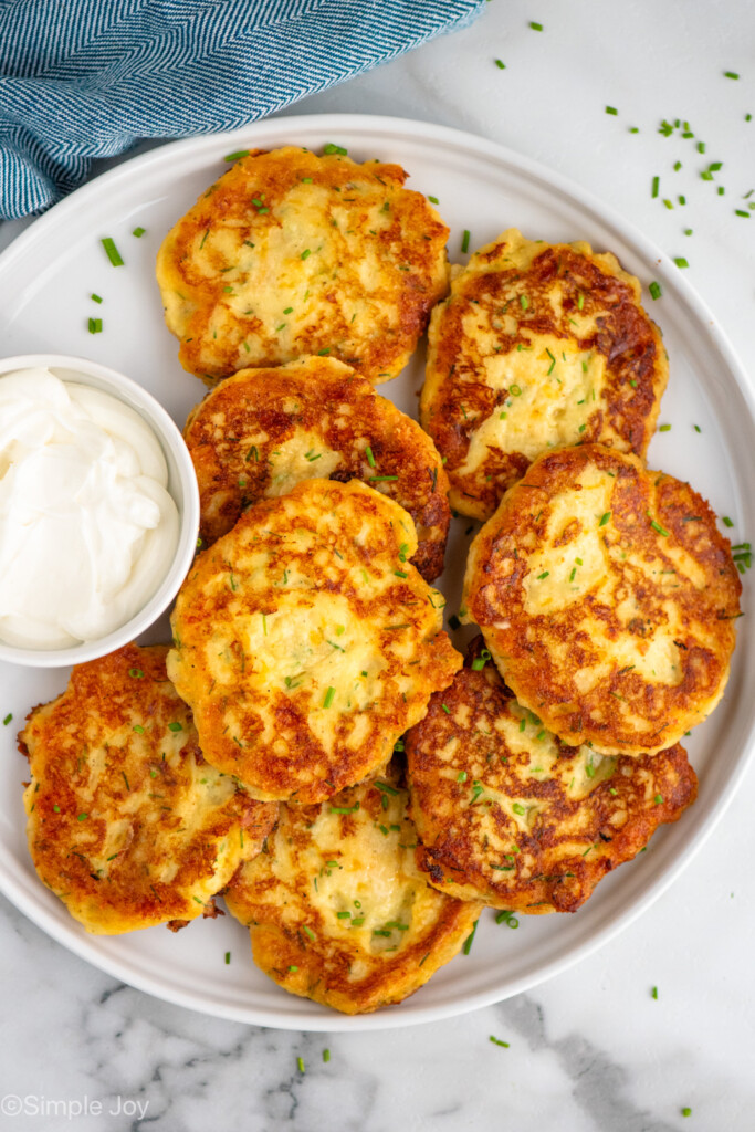 Overhead view of a plate of Mashed Potato Pancakes with bowl of sour cream beside - 9