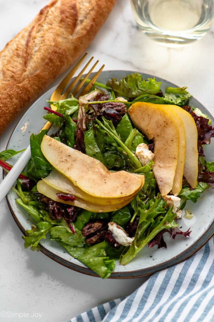 Plate of Pear Salad with fork, loaf of bread and glass of white wine beside - 8