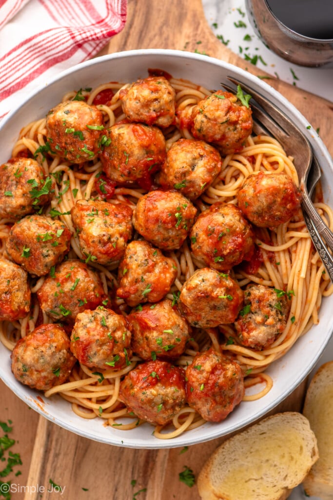 Overhead view of a bow of spaghetti and Baked Turkey Meatballs with sauce, bread beside. - 3