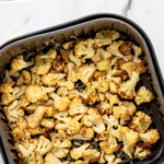 pinterest graphic of overhead air fried cauliflower in the basket of the air fryer, says "air fryer cauliflower recipe simplejoy.com"