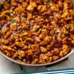 Pinterest graphic for Bourbon Chicken recipe. Image shows a skillet of Bourbon Chicken garnished with sesame seeds and chopped green onions. Text says, "Bourbon Chicken simplejoy.com."