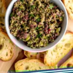 Pinterest graphic for Olive Tapenade recipe. Image shows overhead view of bowl of Olive Tapenade surrounded by toasted bread. Text says, "Olive Tapenade simplejoy.com."