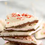 Pinterest graphic for Peppermint Bark recipe. Text says, "the best Peppermint Bark simplejoy.com." Image shows a stack of Peppermint Bark topped with crushed candy canes, with whole candy canes beside.