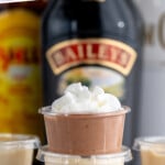 Pinterest graphic for Pudding Shots recipe. Text says, "super simple Pudding Shots simplejoy.com." Image shows side view of a stack of Pudding Shots garnished with whipped cream.