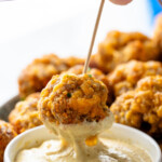 Pinterest graphic for Sausage Balls recipe. Text says, "3 ingredient Sausage Balls simplejoy.com." Image shows person's hand dipping Sausage Ball on toothpick into dipping sauce.