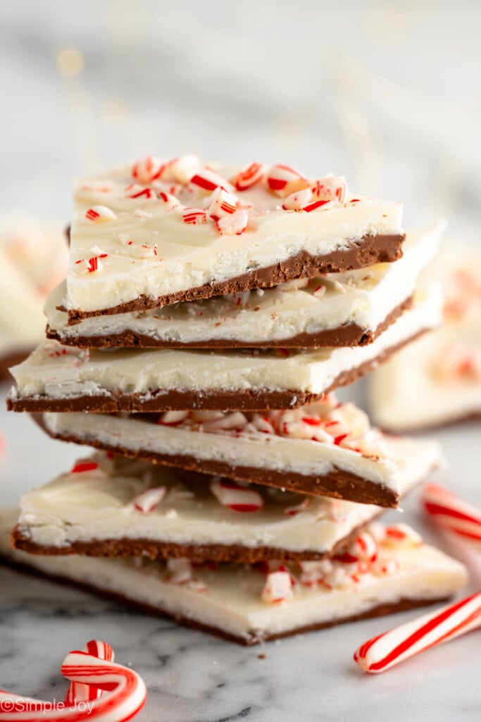 Side view of stack of Peppermint Bark topped with crushed candy canes, with candy canes beside. - 6