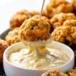 Side view of person's hand dipping Sausage Ball on toothpick into dipping sauce. - 12
