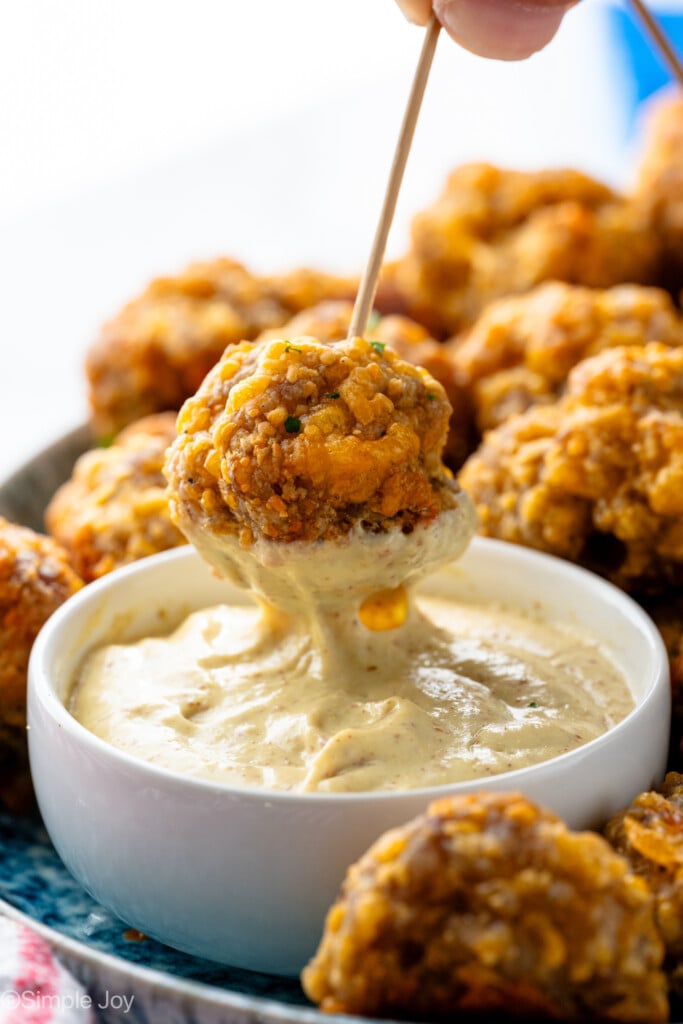 Side view of person's hand dipping Sausage Ball on toothpick into dipping sauce. - 10