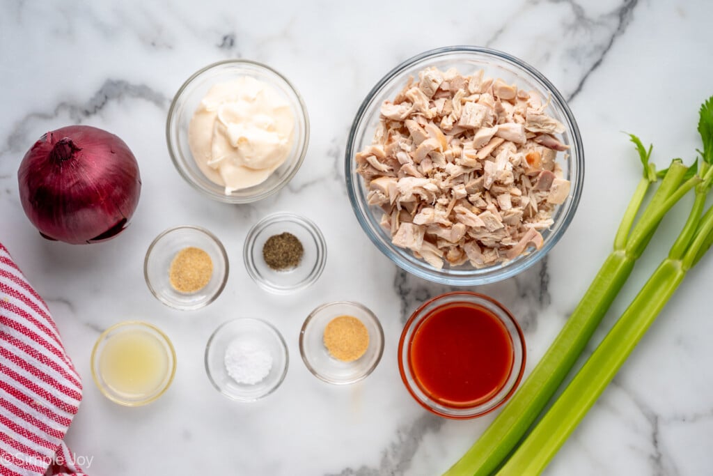 Overhead view of ingredients for Buffalo Chicken Salad recipe on countertop. - 5