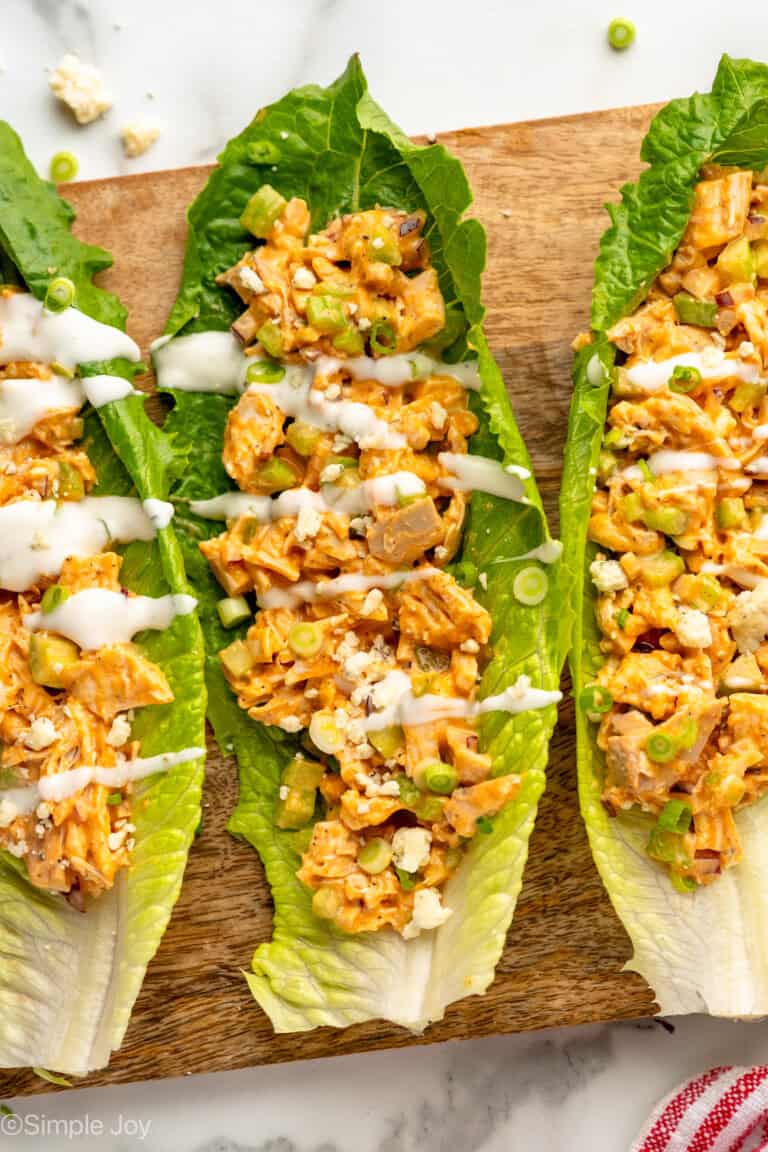 Overhead view of lettuce topped with Buffalo Chicken Salad garnished with blue cheese crumbles and dressing.