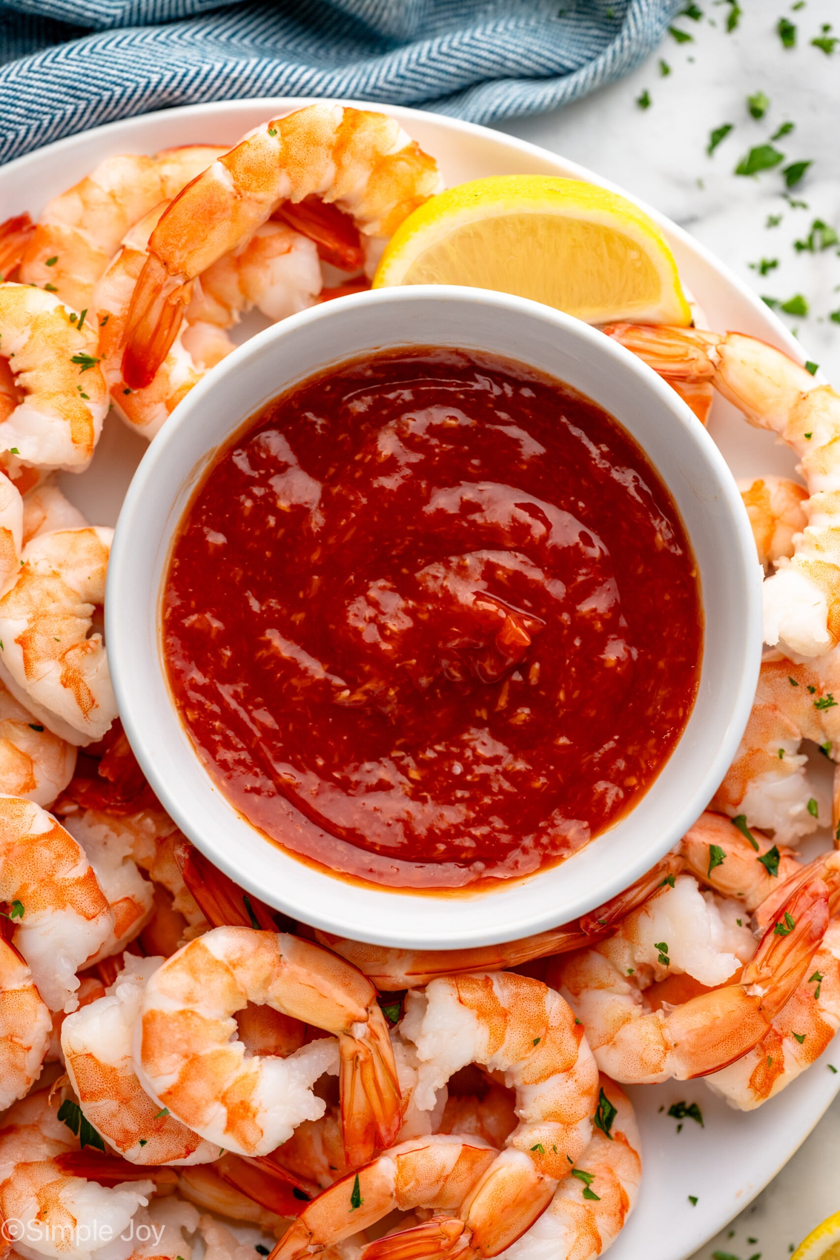 Overhead view of a platter of shrimp and lemon wedge with a bowl of Shrimp Cocktail Sauce - 3