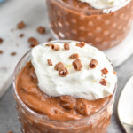 close up of a small cup of chocolate pudding recipe filled topped with whipped cream and chocolate shavings