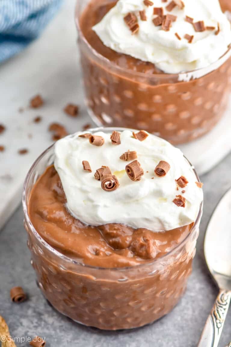 close up of a small cup of chocolate pudding recipe filled topped with whipped cream and chocolate shavings