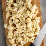 Overhead view of cutting board with cut up cauliflower and a knife for how to cut cauliflower recipe - 7