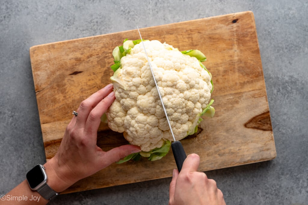 Overhead view of person's hands cutting up head of cauliflower. - 2