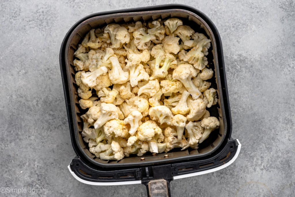 overhead of air fryer basket with uncooked cauliflower in it - 8