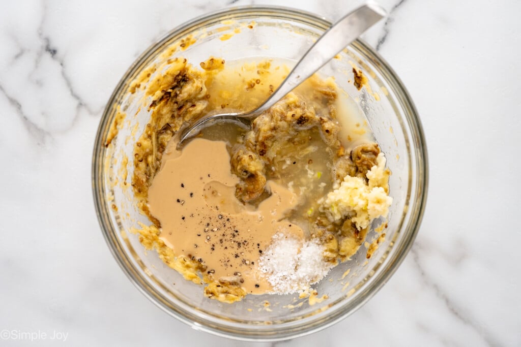 Overhead view of a mixing bowl with ingredients and a spoon for Baba Ganoush recipe