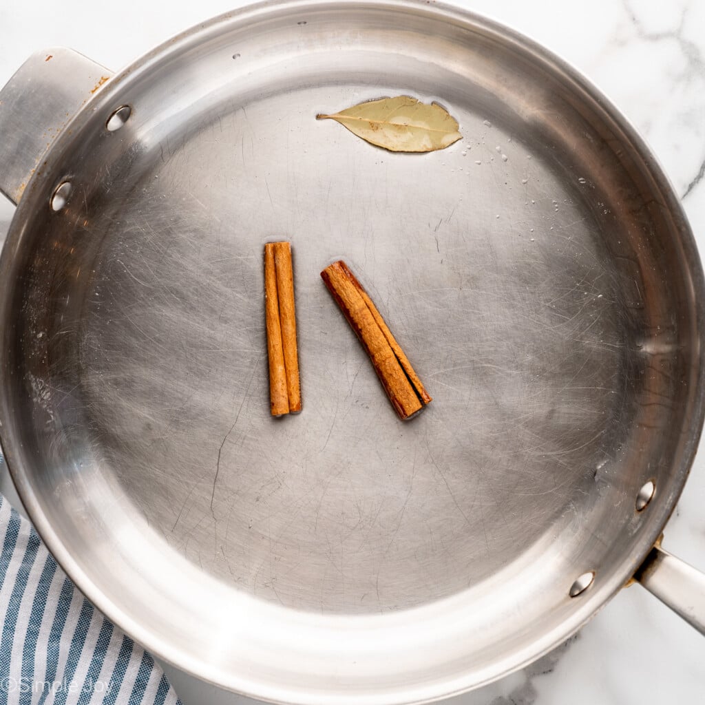 Overhead view of skillet of cinnamon sticks and bay leaf for Chicken Curry recipe - 5