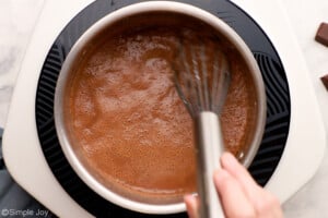 overhead of stirring a saucepan full of chocolate for pudding