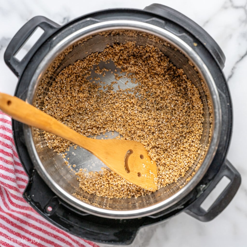 Overhead view of instant pot with ingredients and wooden spoon for Instant Pot Steel Cut Oats recipe