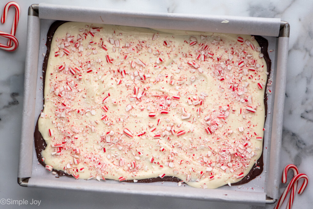 Overhead view of a baking sheet of Peppermint Bark recipe topped with crushed candy canes, candy canes beside. - 10