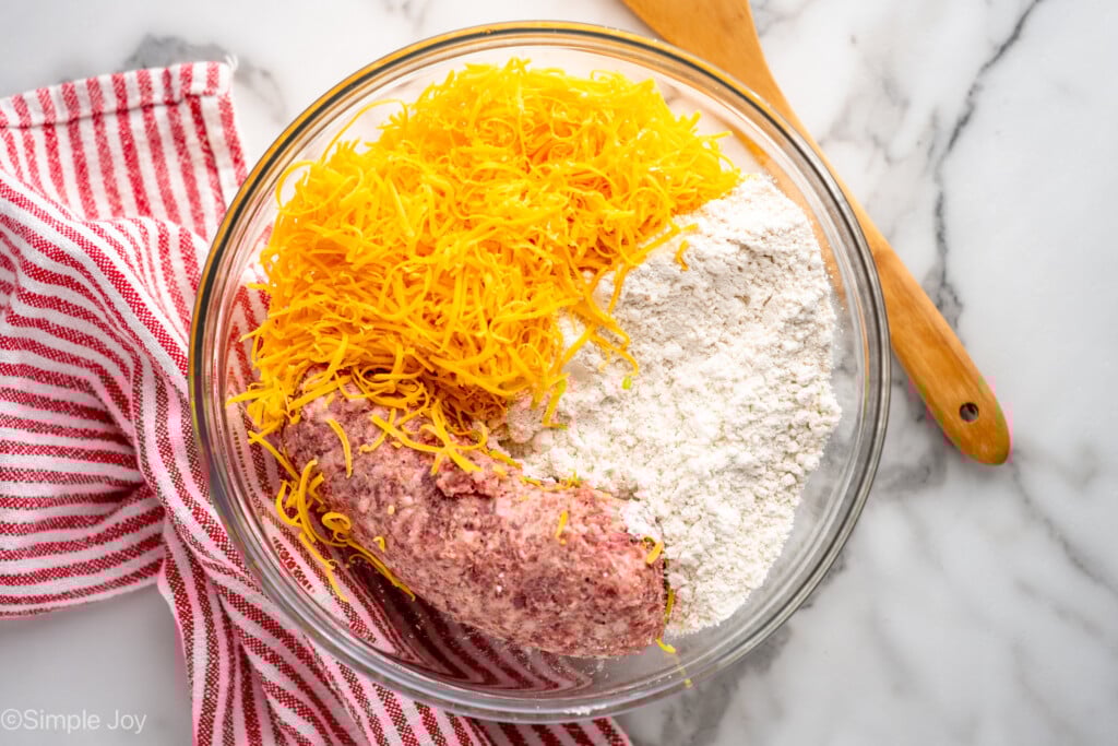 Overhead view of mixing bowl of ingredients for Sausage Balls recipe, wooden spoon beside. - 6