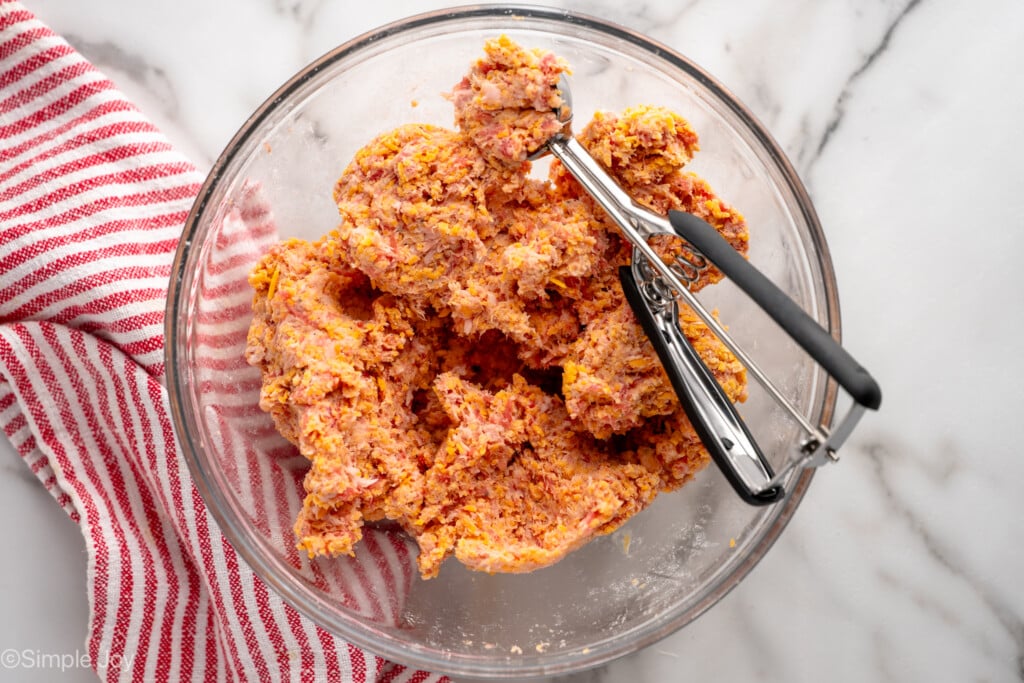 Overhead view of mixing bowl of Sausage Balls ingredients with cookie scoop before baking. - 7