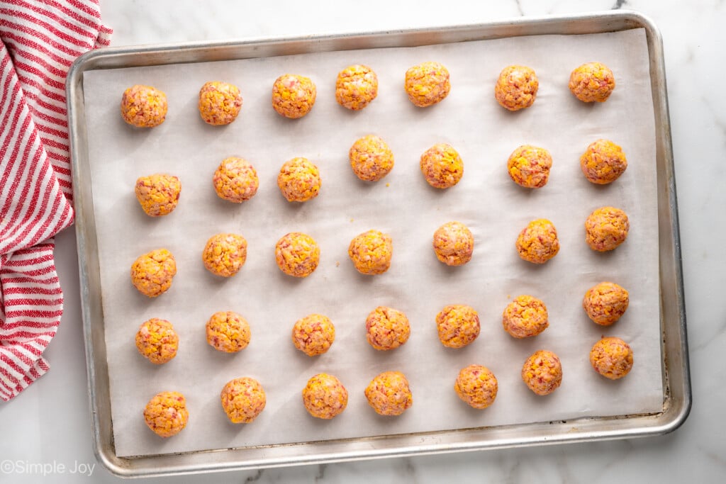 Overhead view of a baking sheet lined with parchment paper with Sausage Balls recipe before baking. - 8