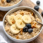 Bowl of Instant Pot Steel Cut Oats topped with sliced banana and blueberries, spoon for eating. - 12