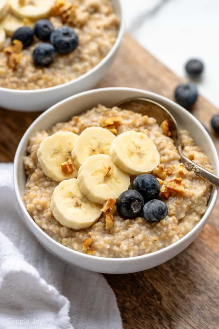 Bowl of Instant Pot Steel Cut Oats topped with sliced banana and blueberries, spoon for eating.