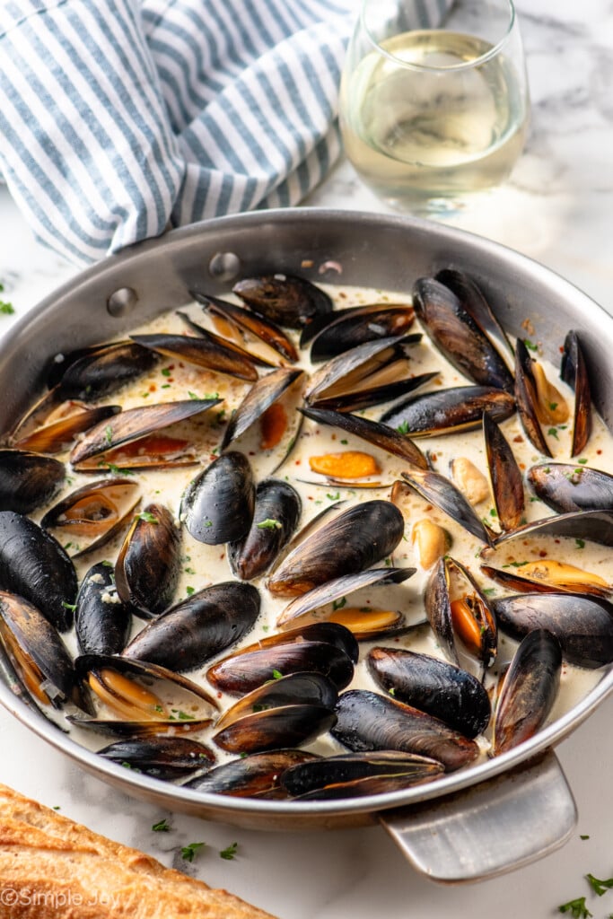 Skillet of Mussels recipe with loaf of bread and glass of white wine beside - 9