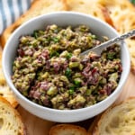 Bowl of Olive Tapenade with a knife for spreading on platter of toasted bread. - 10