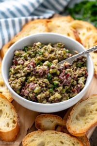 Bowl of Olive Tapenade with a knife for spreading on platter of toasted bread. - 9