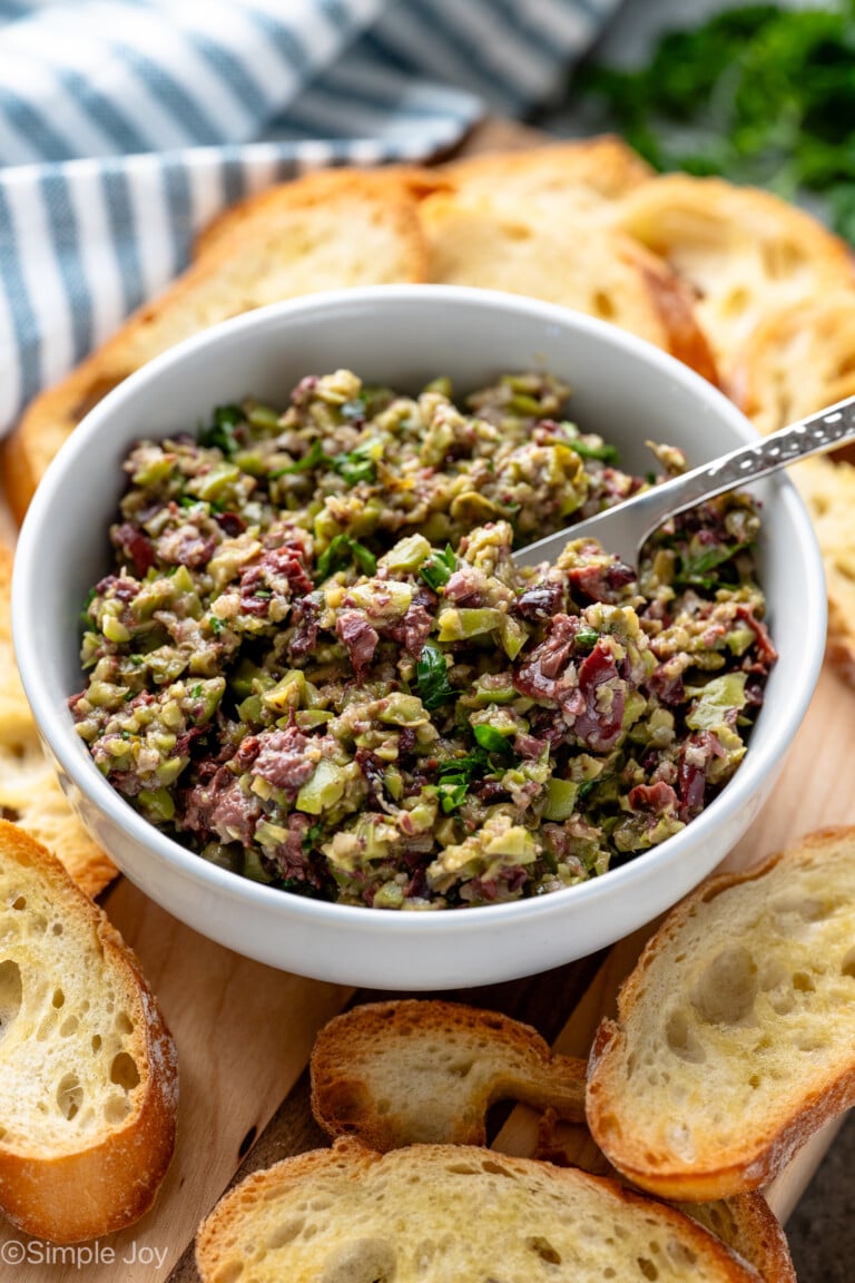 Bowl of Olive Tapenade with a knife for spreading on platter of toasted bread.
