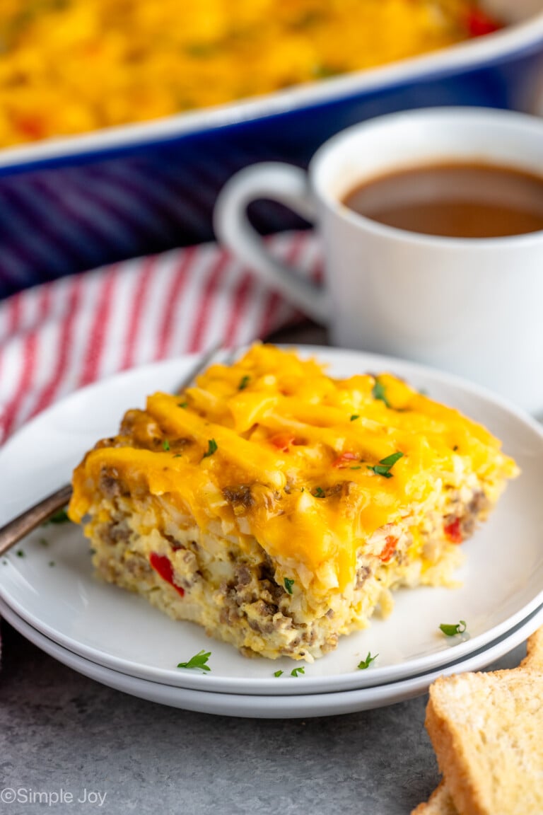 Piece of Hashbrown Breakfast Casserole served on a plate with a fork, cup of coffee beside.