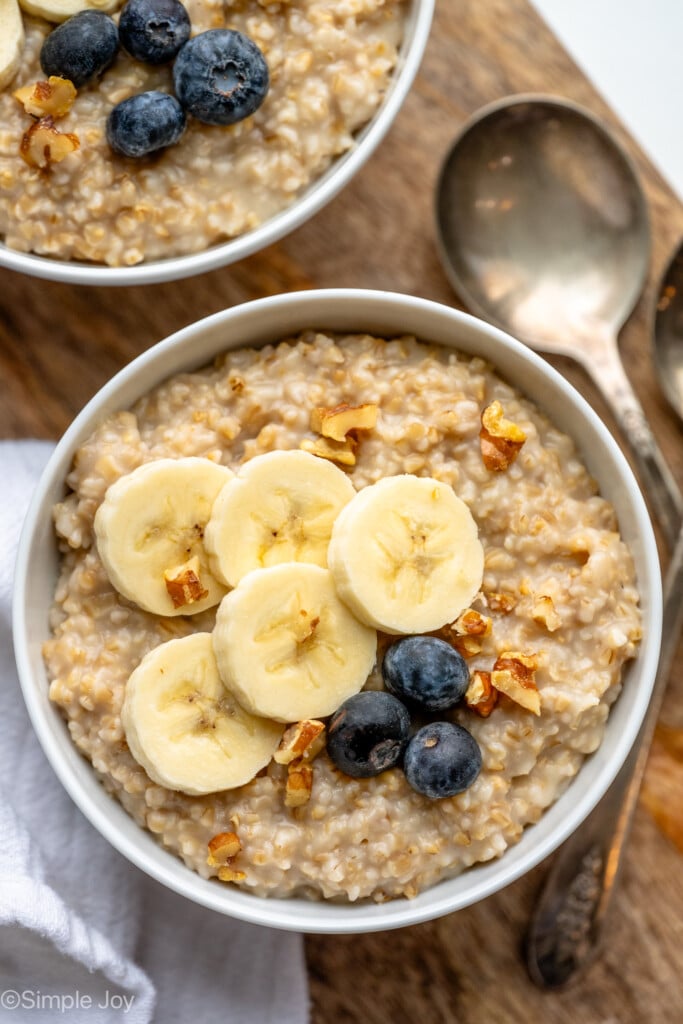 Overhead view of a bowl of Instant Pot Steel Cut Oats topped with sliced banana and blueberries, spoons beside. - 10