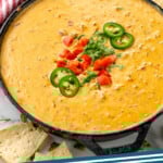 Pinterest graphic for Rotel Dip recipe. Image shows a skillet of Rotel Dip garnished with chopped tomatoes, cilantro, and jalapenos. Tomatoes and tortilla chips beside. Text says, "Rotel Dip simplejoy.com."