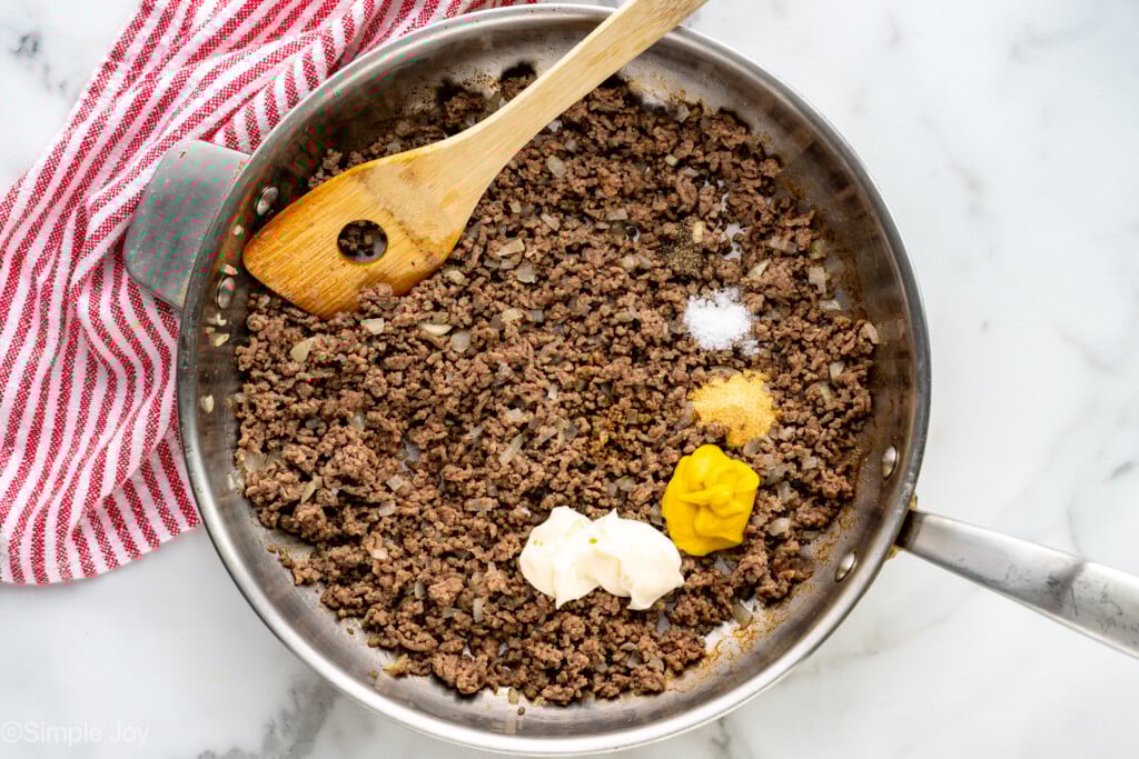 Overhead view of a skillet of ingredients and wooden spoon for Cheeseburger Sliders recipe - 6