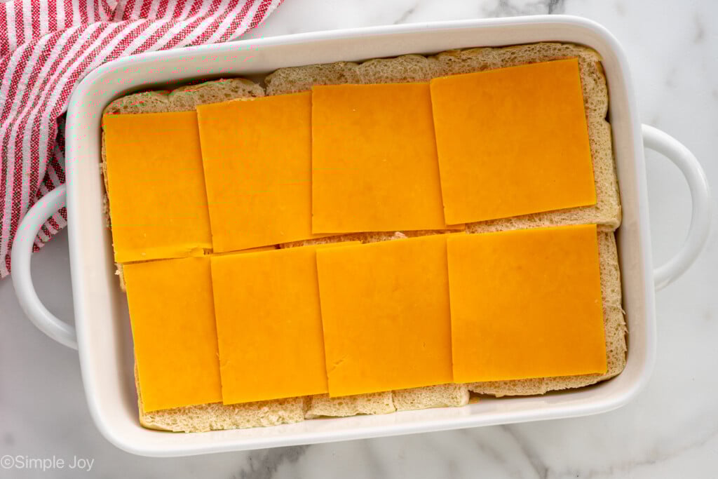 Overhead view of baking dish with cheese layer for Cheeseburger Sliders recipe